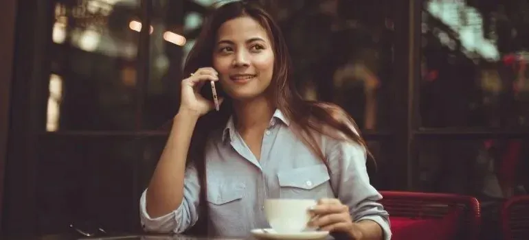 Woman with coffee talking on phone at cafe