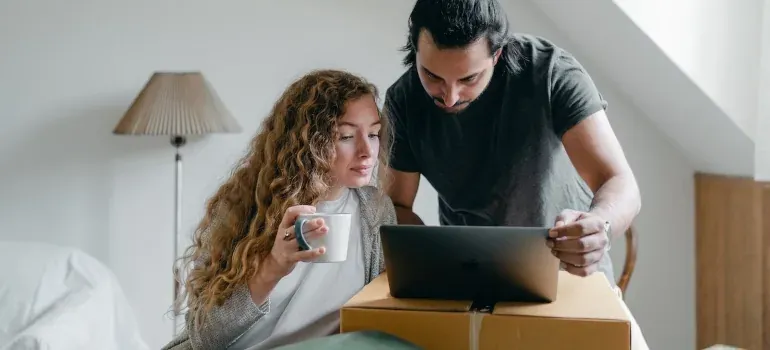 Couple browsing laptop on box