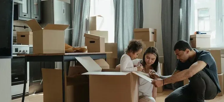 Parents and child writing on moving boxes at home