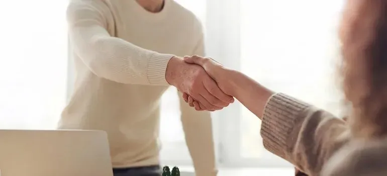 Two people shaking hands in a bright office