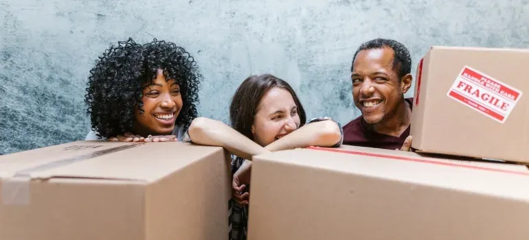 Three friends laughing behind boxes