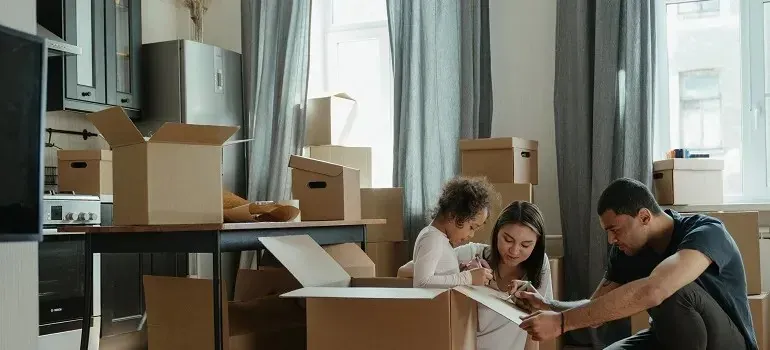 Family with child unpacking boxes in kitchen, duplicate scene