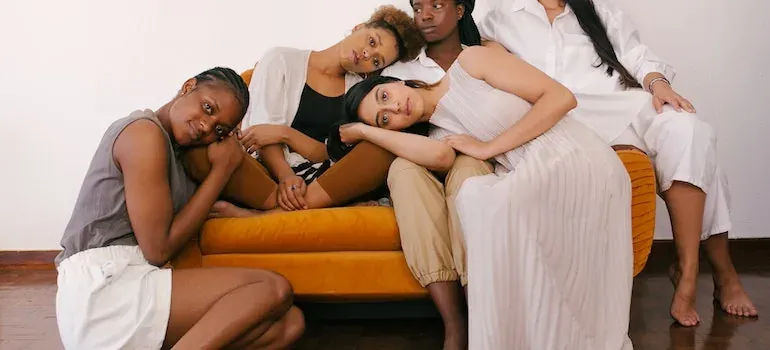 Five women posing on orange sofa