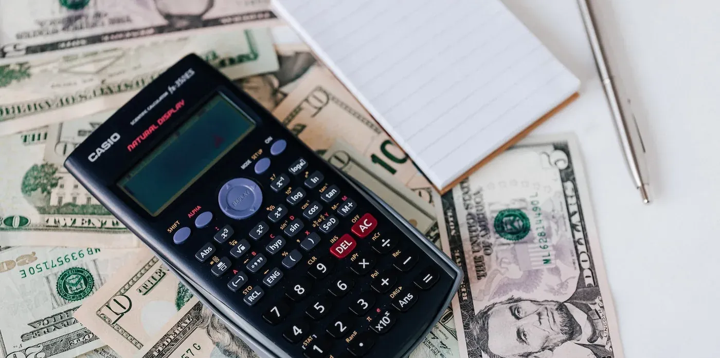 Casio calculator on dollar bills, notepad