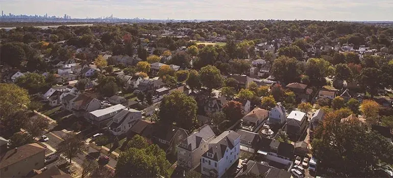 Aerial view of leafy suburban neighborhood, city skyline beyond