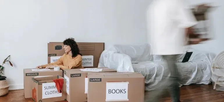Labeled moving boxes and plastic-covered sofa in living room