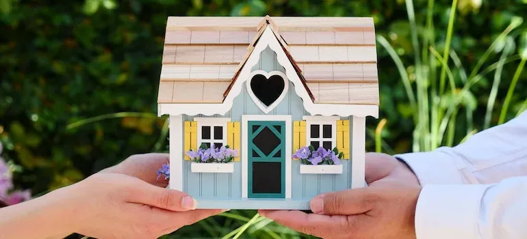 Hands holding miniature model house