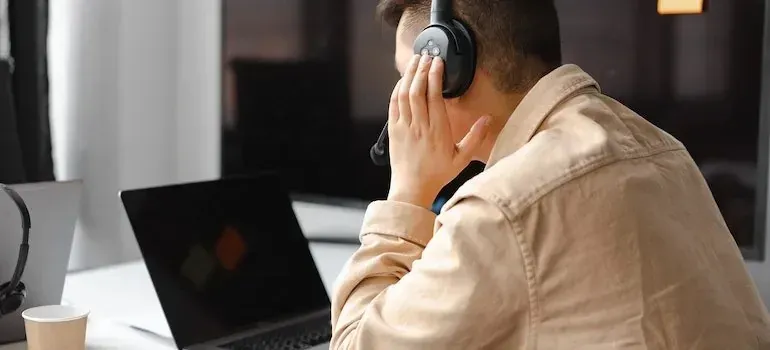 Man wearing headset at laptop, customer service scene