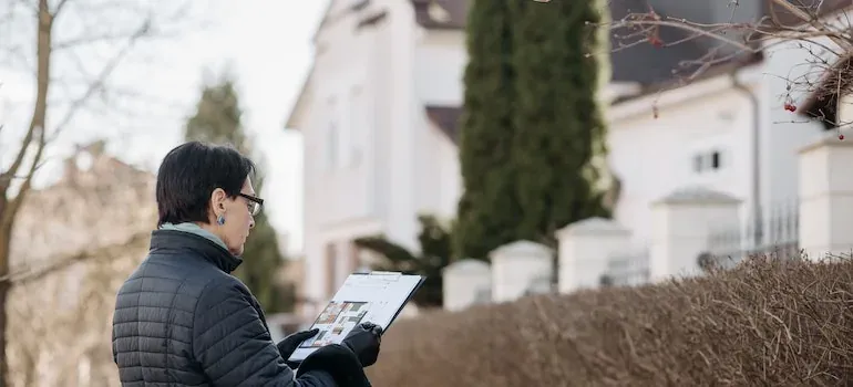Woman with clipboard outside houses