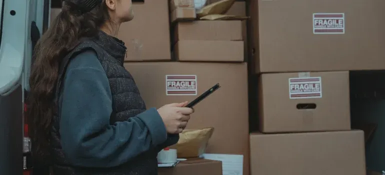 Woman with tablet by fragile-labeled boxes