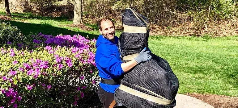 Mover hugging padded wrapped statue by flowers