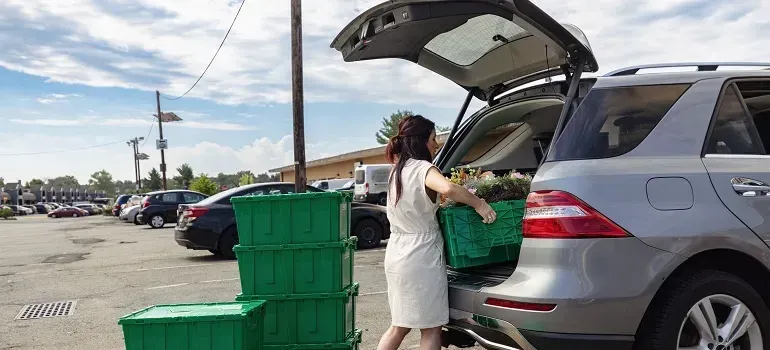 Woman loading green plastic bins into SUV