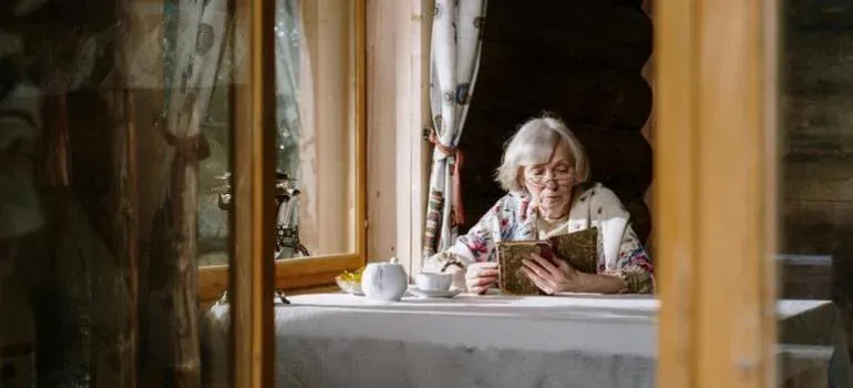 Elderly woman reading book at table