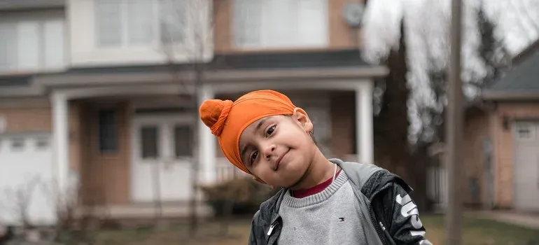 Sikh boy in orange patka outside house