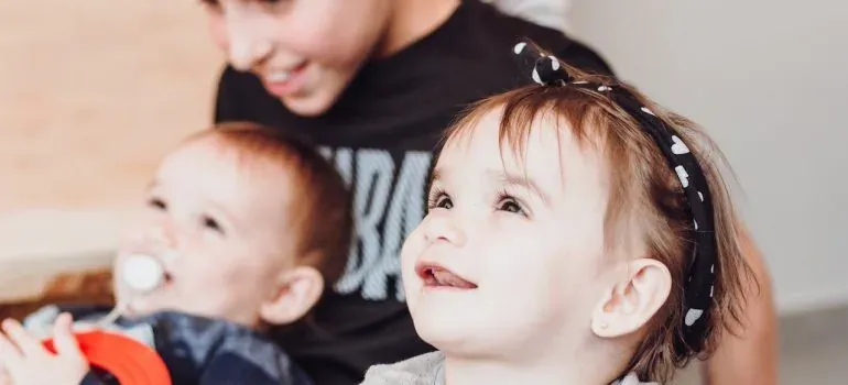 Toddlers smiling with older sibling