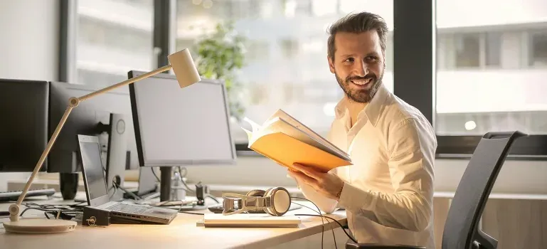 Man at office desk holding book