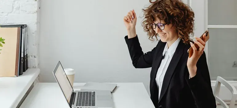 Cheerful businesswoman celebrating at laptop