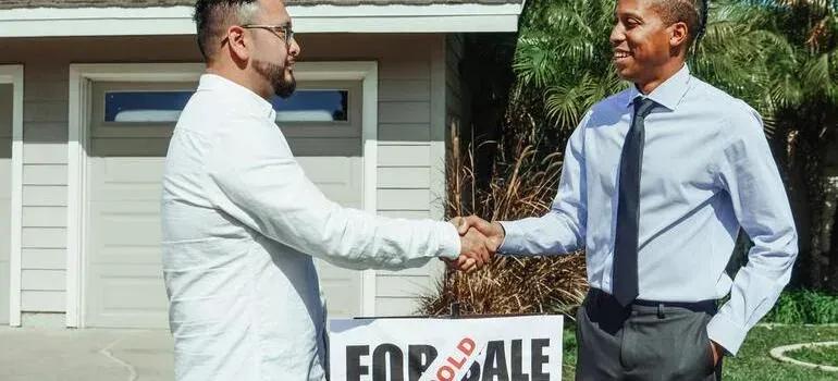 Handshake over sold sign at house