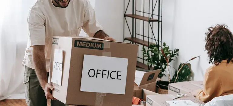 Man carrying OFFICE labeled moving box