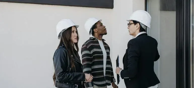 Three people in hard hats outside building