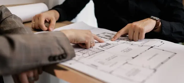 Hands pointing at floor plan blueprint