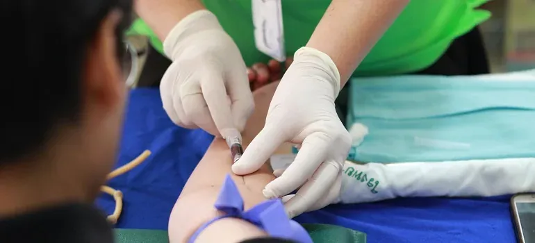 Gloved nurse drawing blood from arm