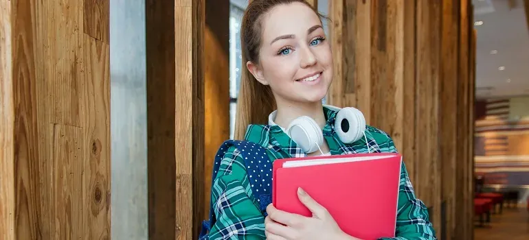Student with headphones holding red notebook