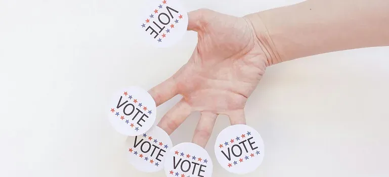Hand with VOTE stickers on white