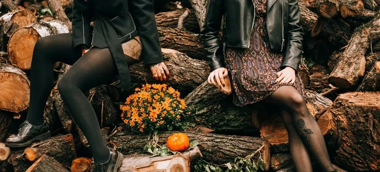 Two women seated on logs, autumn pumpkin