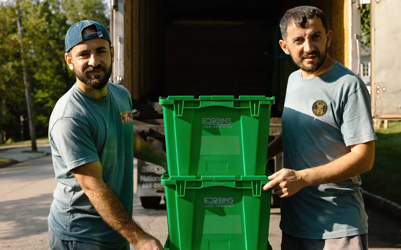 Two Teddy Bear Moving crew members at the truck with a stack of moving bins