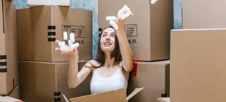 Woman tossing packing peanuts among boxes
