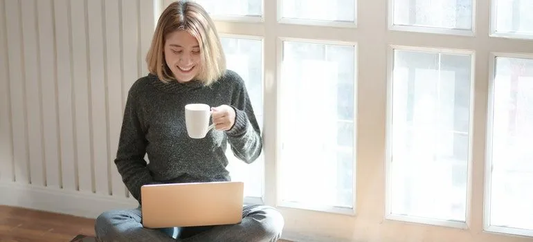Person shopping on a laptop at home with a cup of coffee