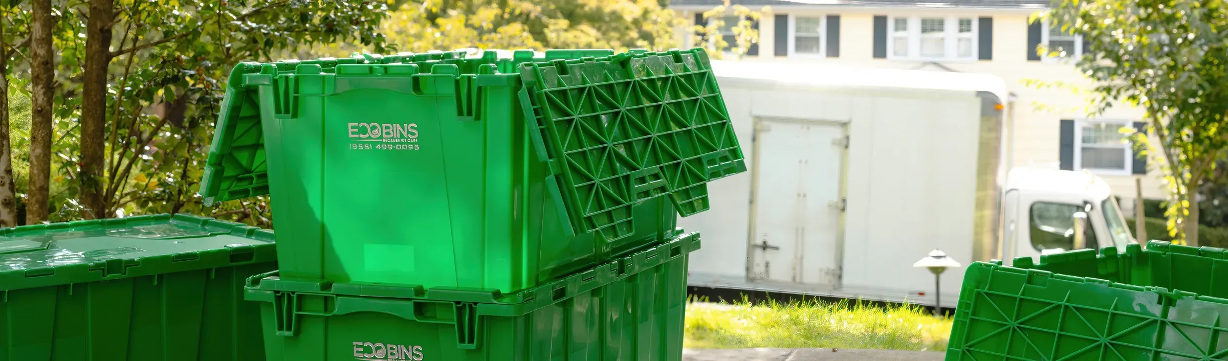 Green EcoBins bins waiting in a driveway beside the moving truck