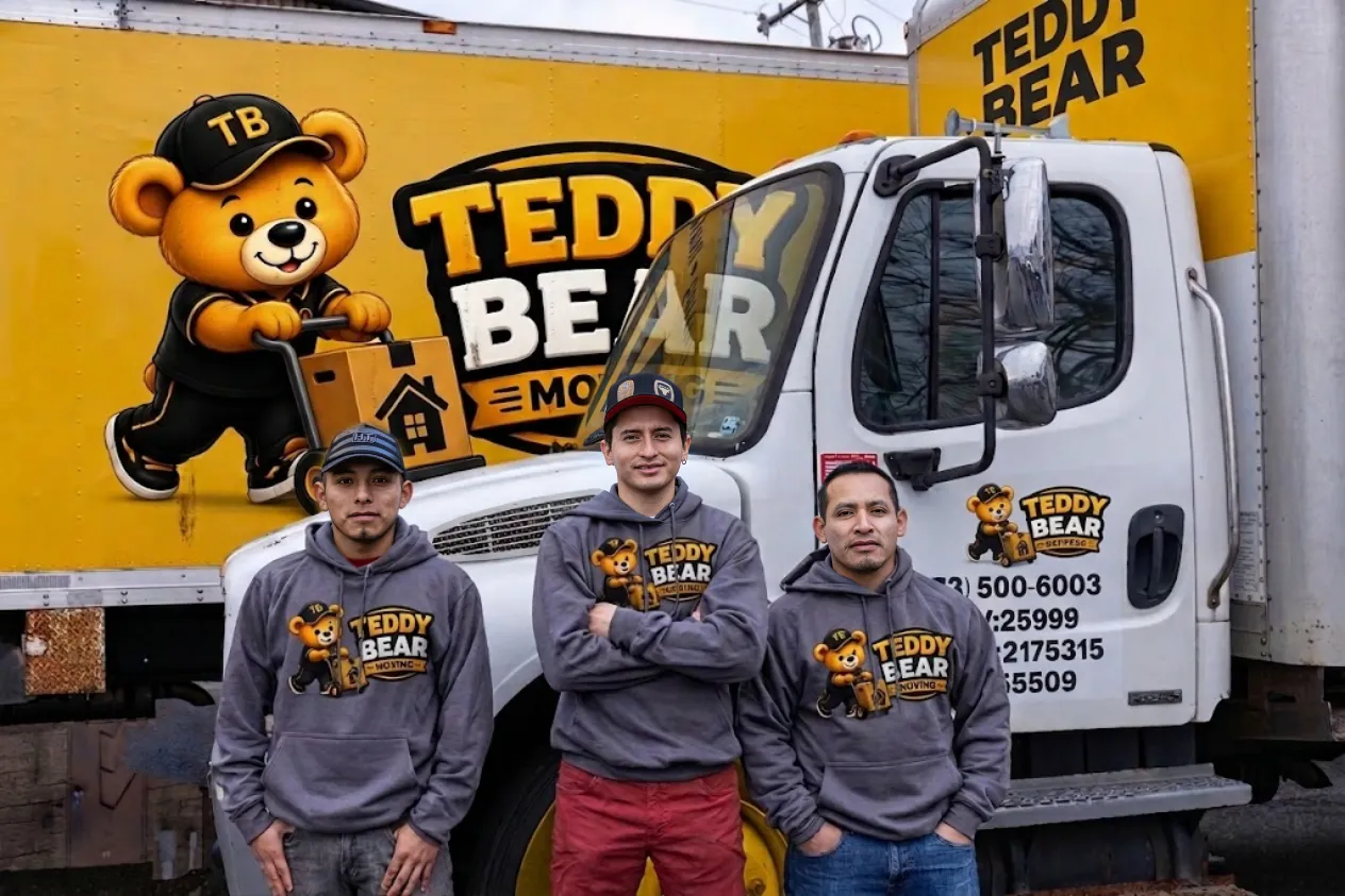 Three Teddy Bear Moving crew members standing in front of branded moving trucks