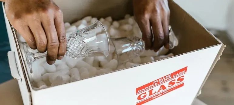 Hands packing glassware in GLASS-labeled box