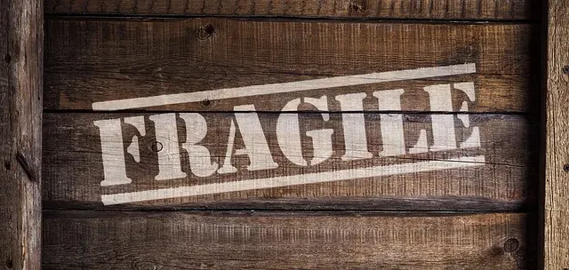 Movers wrapping fragile glassware in packing paper before a move
