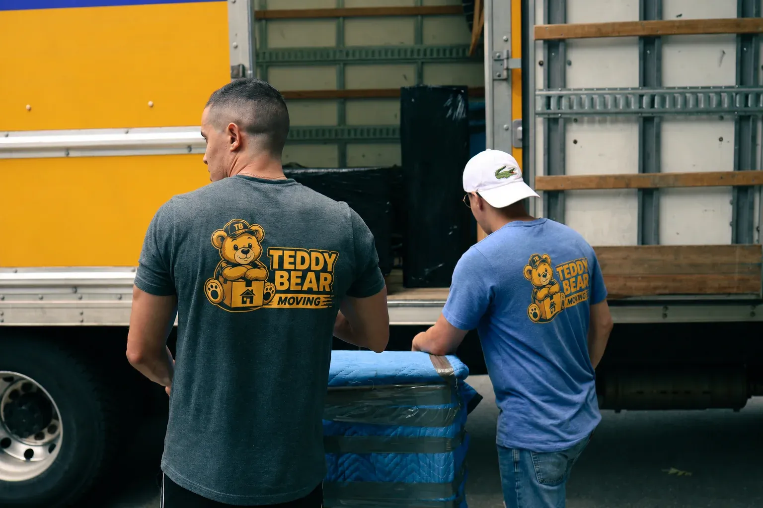 A Teddy Bear Moving crew member loading a wrapped item into the truck