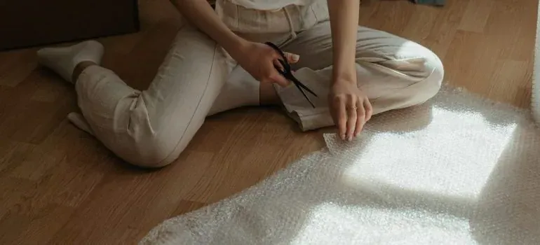 Woman cutting bubble wrap on floor