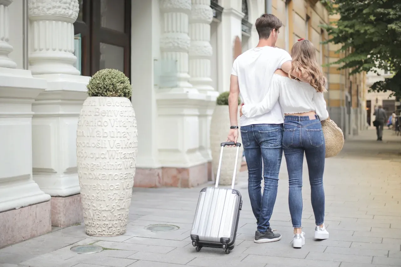 Couple with suitcase walking city street