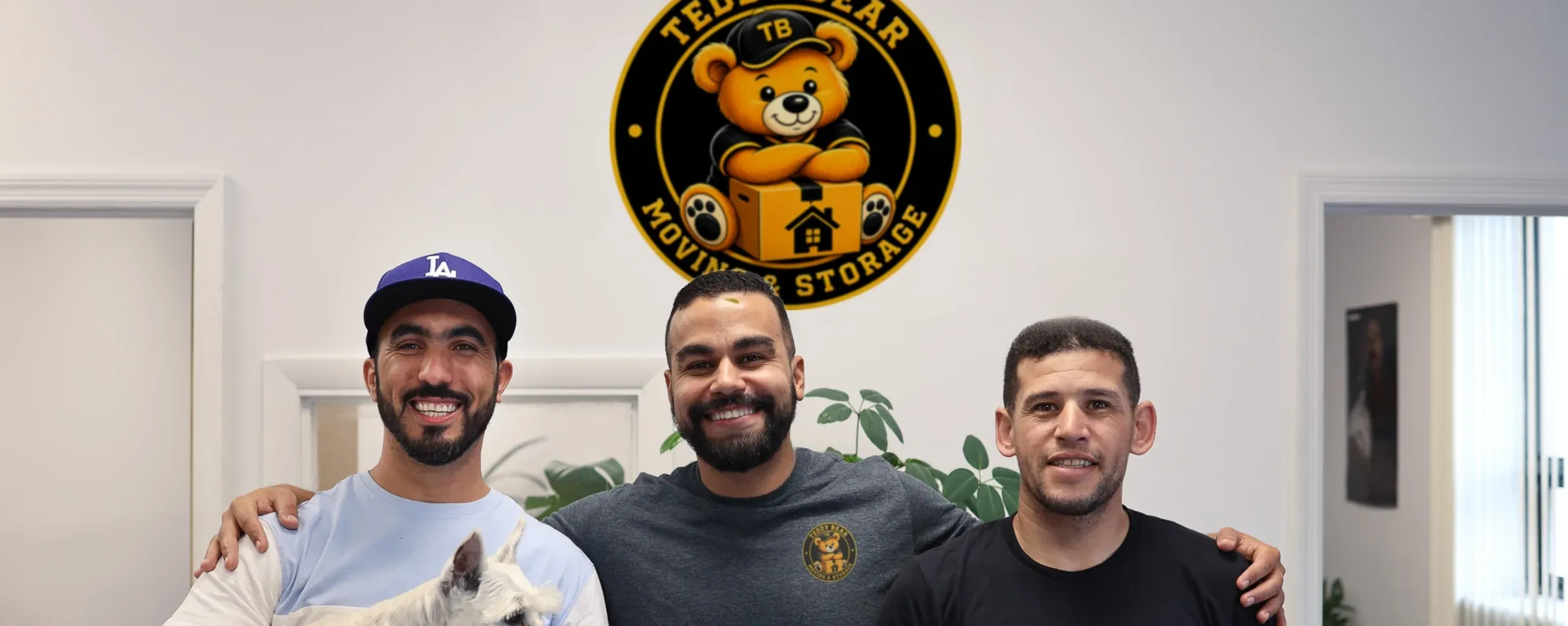 The Teddy Bear Moving team together in the office, under the company sign